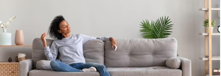 Frau entspannt auf Sofa unter Klimaanlage